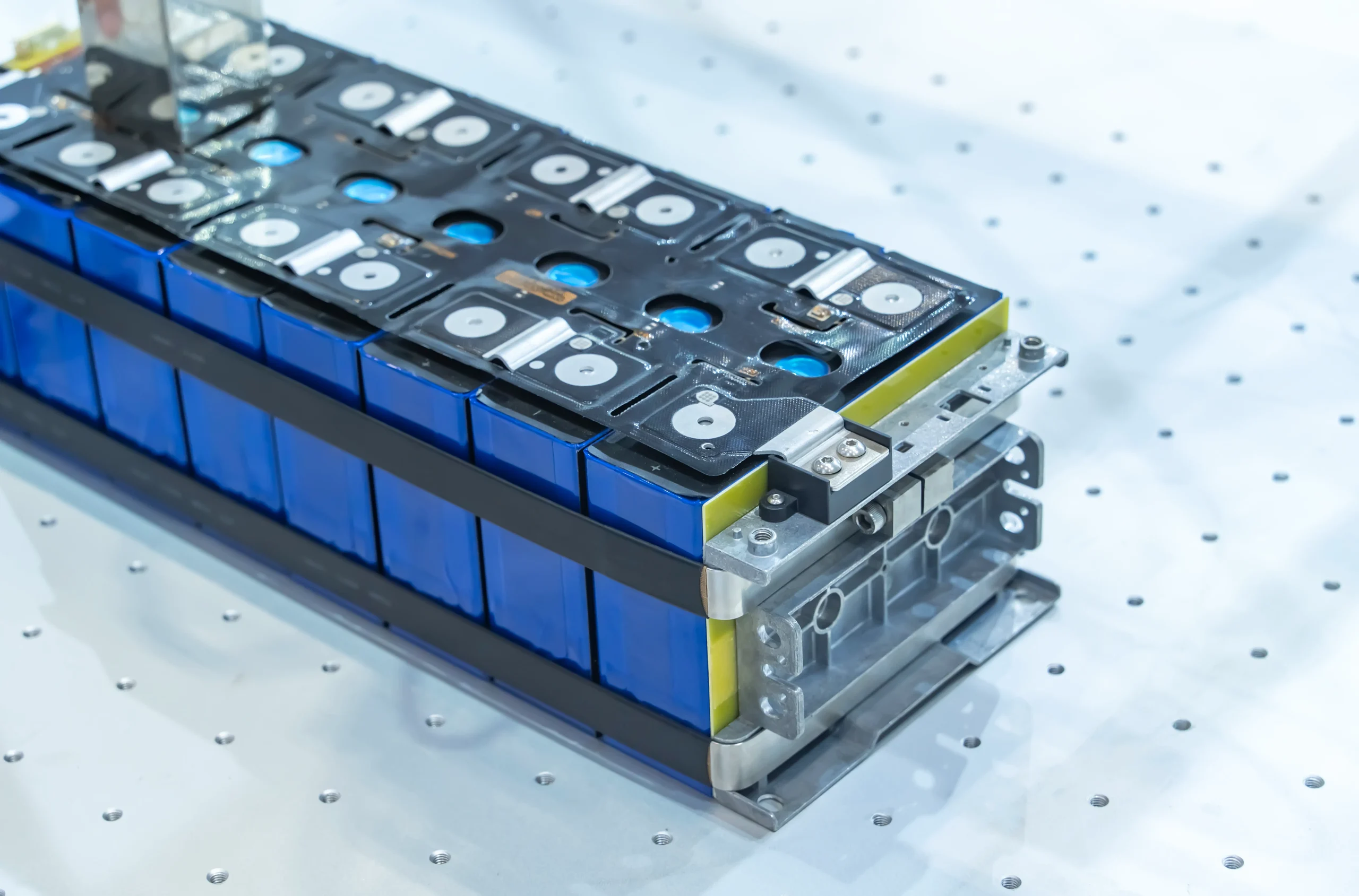 Precision-assembled LiFePO4 battery pack with cobalt blue ABS casings, interconnected by silver busbars and topped with black PCB control board. Mounted on white perforated background demonstrating fsebattery's modular power system design.